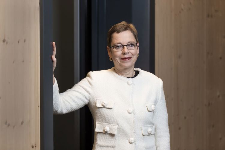 Portrettbilde av Mari Velsand. Hun står ved en vegg, og den høyre armen er løftet mot veggen mens hun ser i kamera. Hun har på seg hvit jakke.