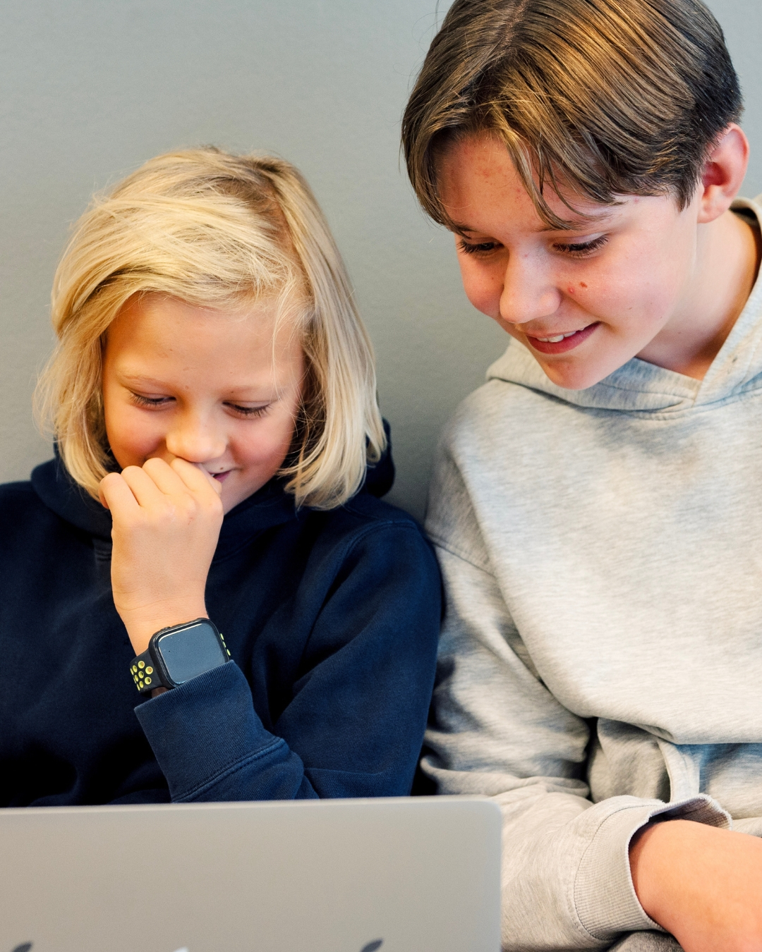 To barn sitter sammen og ser p&aring; en b&aelig;rbar PC.