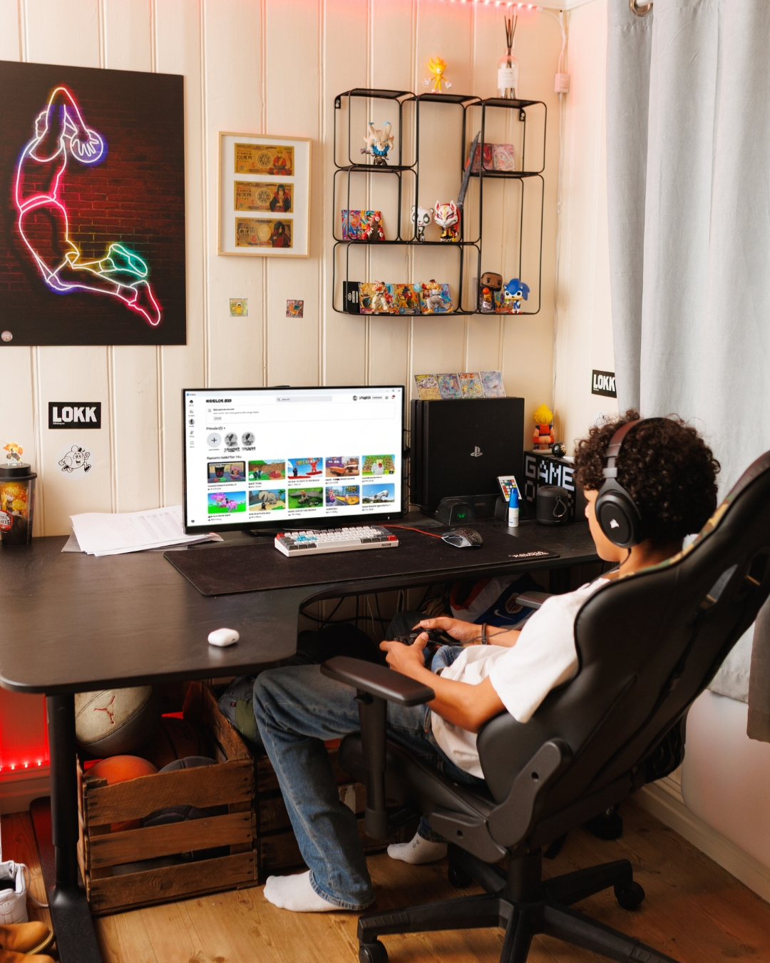 En ungdom sitter ved en PC med hodetelefoner og spiller Roblox ved et skrivebord p&aring; et soverom.