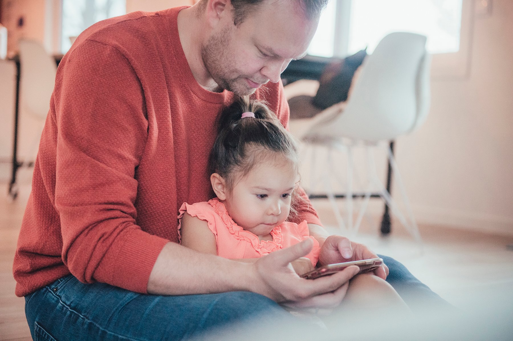 Bildet viser en far med sin lille datter i fanget. Sammen ser de på mobilen. Foto Kine Jensen/ Medietilsynet