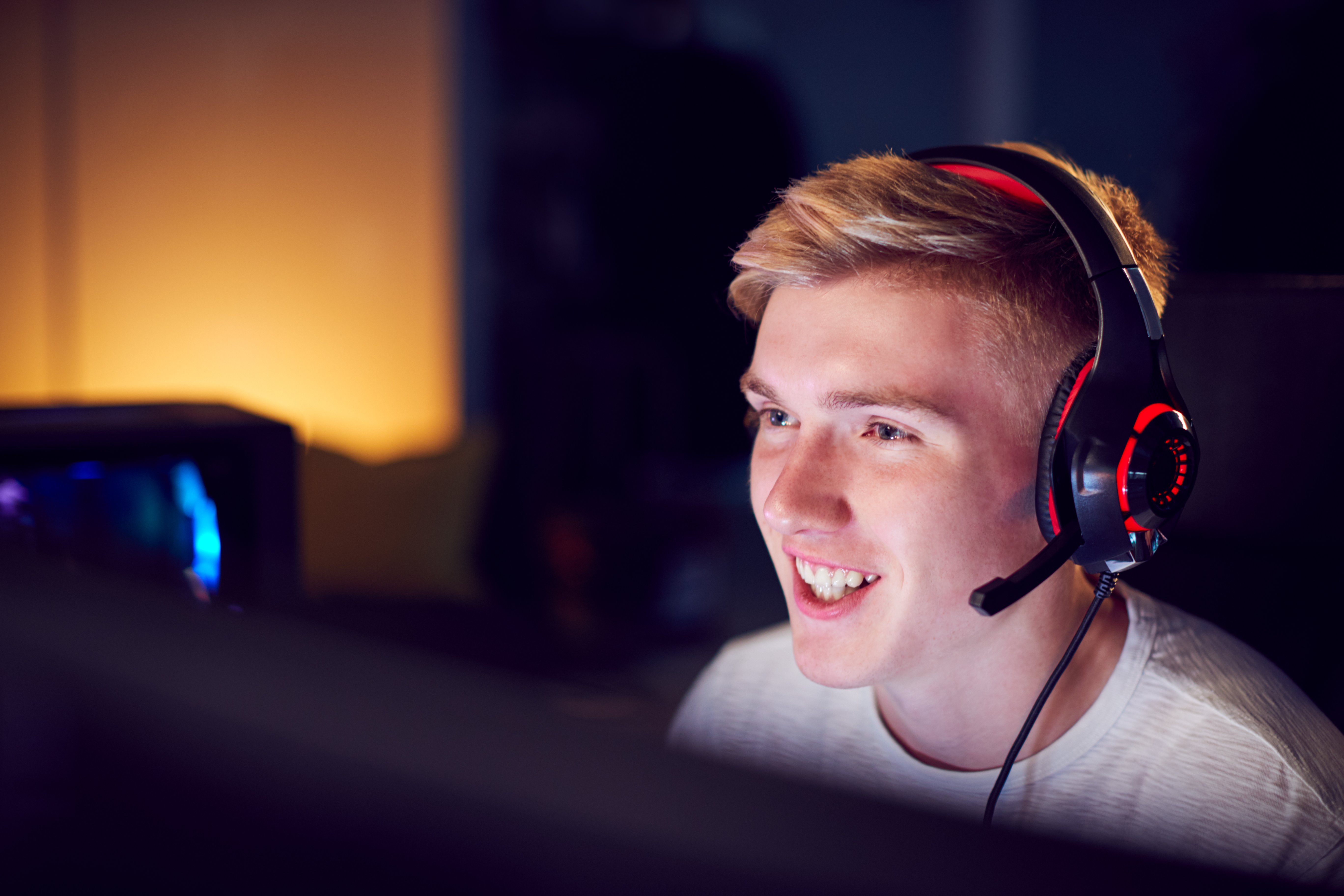 Bildet viser en ung gutt som ler og gamer. Foto iStock