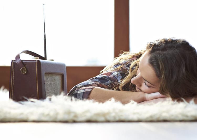 Kvinne ligger og lytter til radio