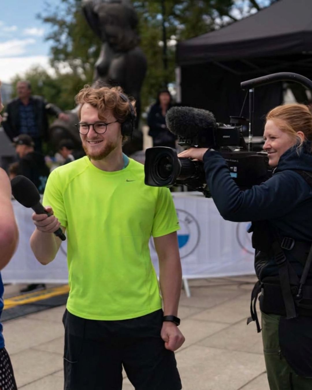 Ein journalist med mikrofon og ein fotograf med videokamera gjennomfører eit intervju utandørs.