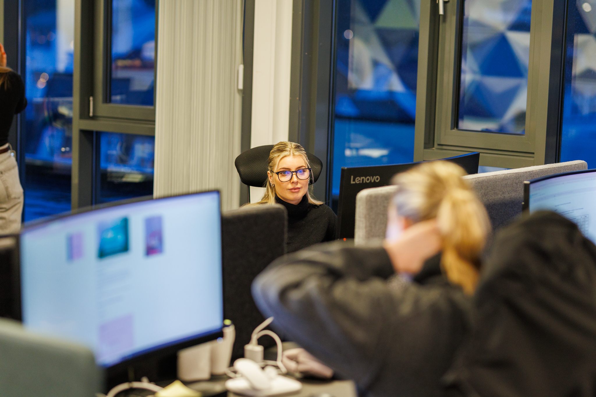 Ansatte jobber foran dataskjermer i et &aring;pent kontorlandskap.