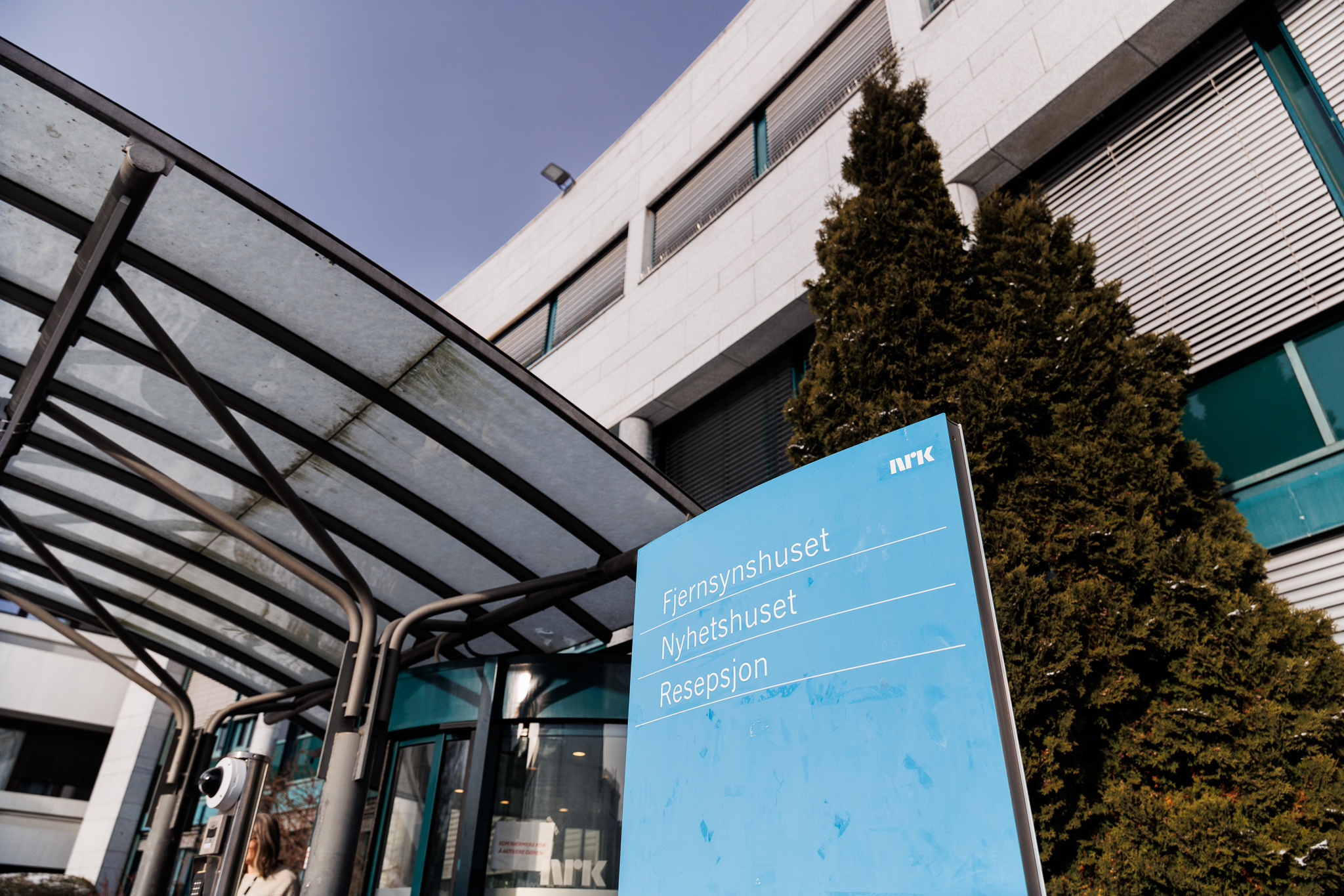Inngangsparti til NRK med skilt som viser vei til ulike avdelinger.
